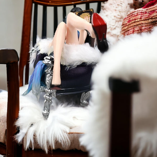 Anime figure sitting on a silver and black decorative chair with fur armrests