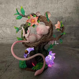 Pokémon Mew figure sleeping on a tree branch with colorful flowers and LED light.