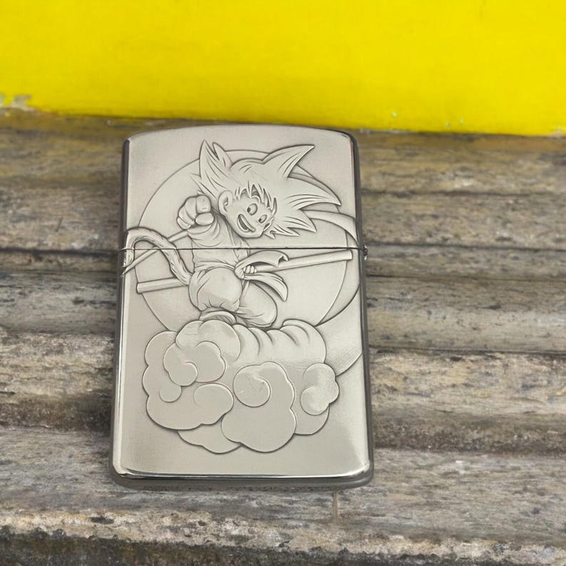 Back view of Zorro 3D metal lighter featuring Goku riding the Flying Nimbus with a minimalist engraved design, placed on a wooden surface.