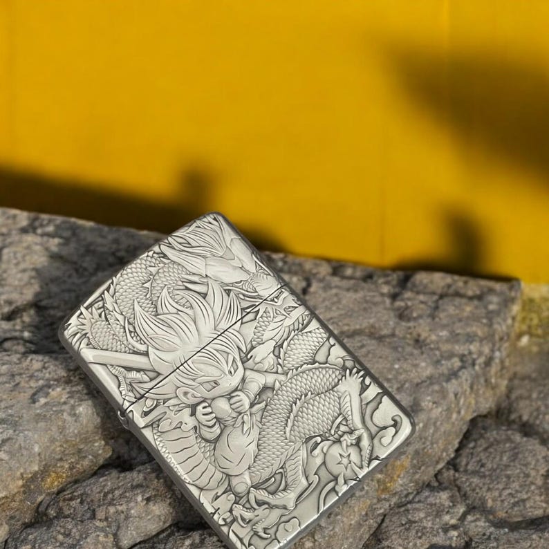 Side-angle view of Zorro 3D metal lighter featuring Goku from Dragon Ball with an intricate dragon relief design, placed on a stone surface.